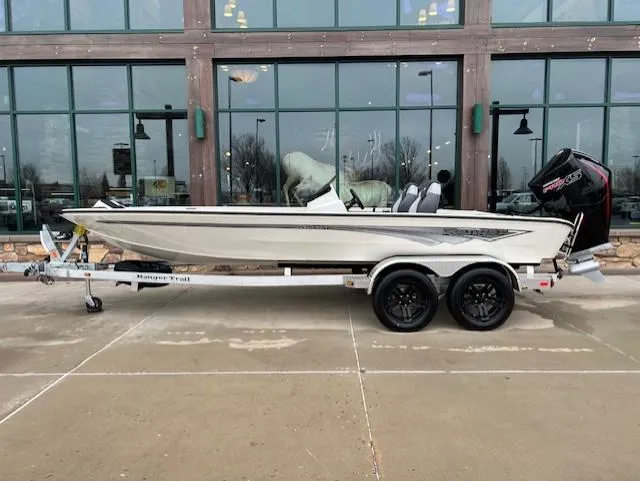 The Image of 2025 Ranger ALPHA 208 boat on trailer, parked outside a building with large windows. - 0