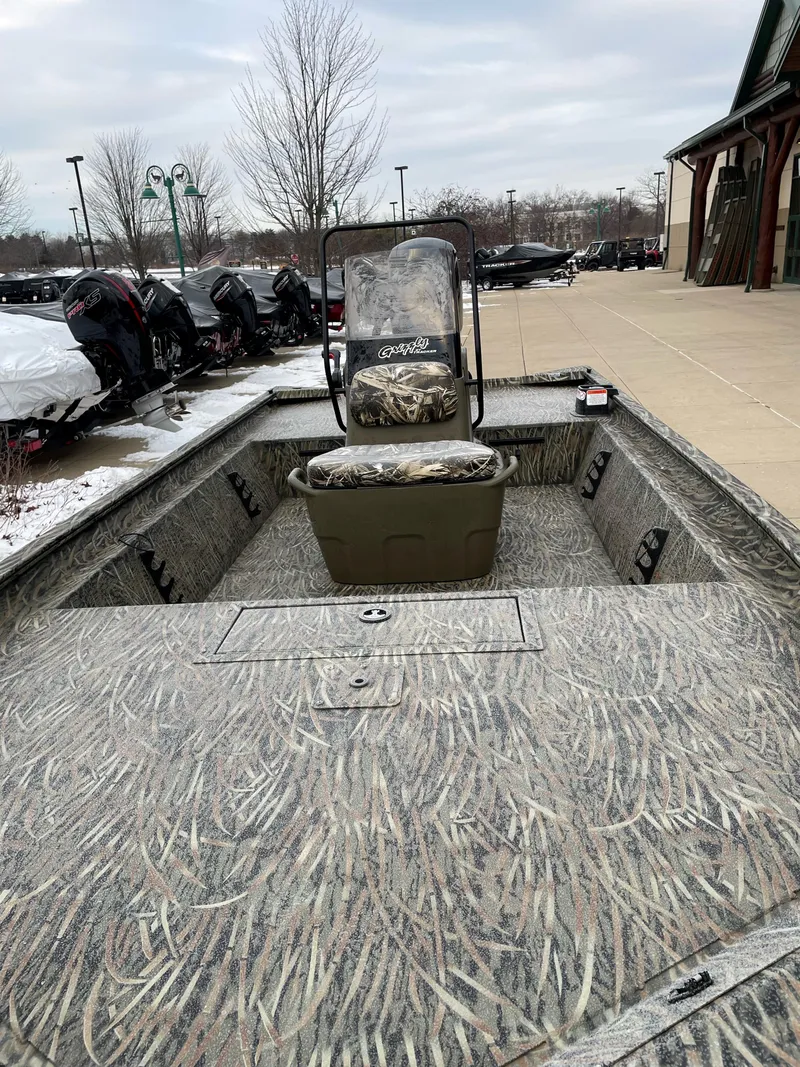Slide: The Image of 2025 Tracker Grizzly 1860 CC boat with camouflage interior, parked outdoors. - 2