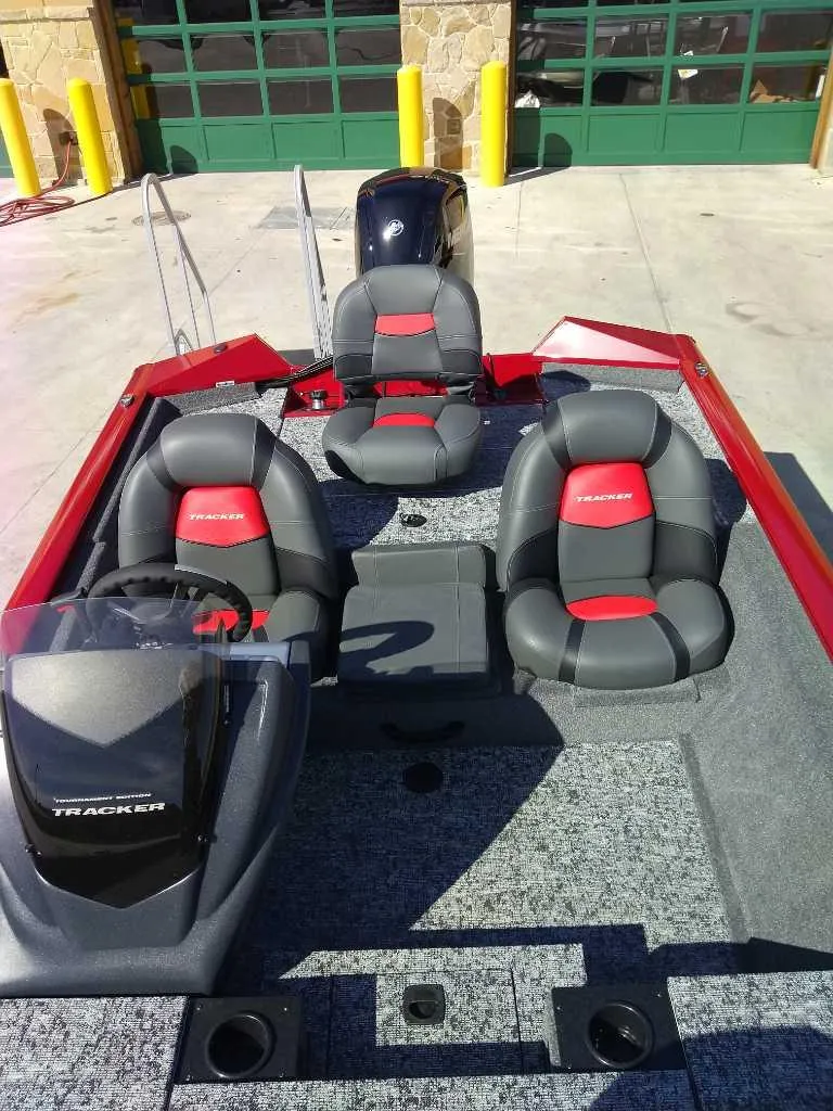 Slide: The Image of 2025 Tracker Pro Team 175 boat with red and gray seating, docked outdoors. - 5