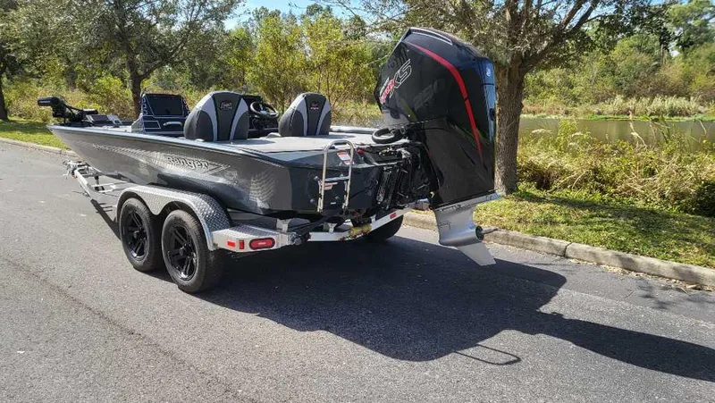 Slide: The Image of 2025 Ranger ALPHA 208 boat on trailer, parked on a sunny road near trees. - 5