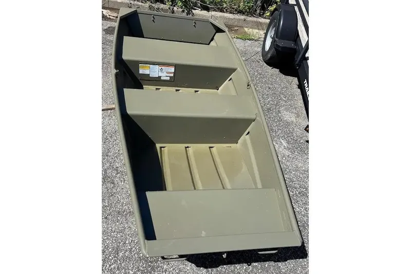 The Image of 2025 Tracker Grizzly 1036 Utility boat on pavement, showcasing interior seating and design. - 0