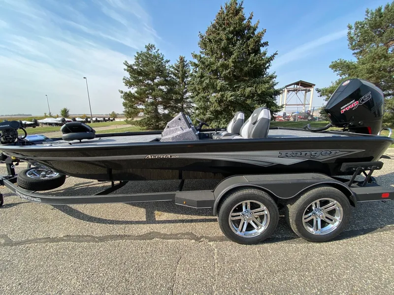 Slide: The Image of 2025 Ranger ALPHA 208 boat on trailer, parked outdoors, with trees in background. - 3