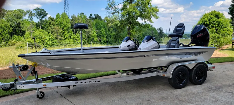 The Image of 2025 Ranger ALPHA 208 boat on trailer, parked outdoors, surrounded by lush greenery. - 0