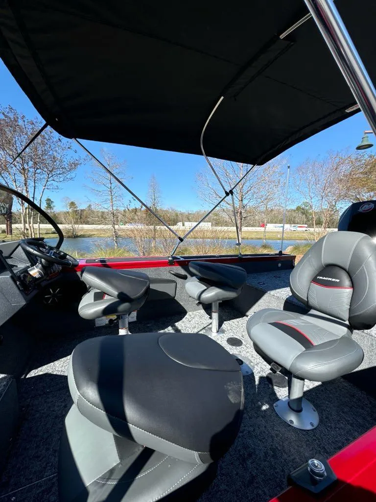 Slide: The Image of 2025 Tracker Targa V-18 WT boat interior with seating, under canopy, near a lake. - 5