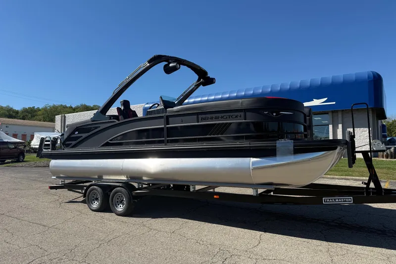The Image of 2025 Bennington M Line pontoon boat on trailer under clear blue sky. - 0