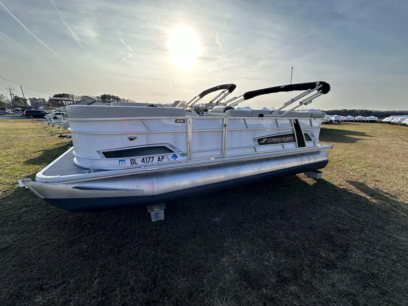 Slide: The Image of 2023 Starcraft EX 20 C pontoon boat on grass under a bright sun. - 0