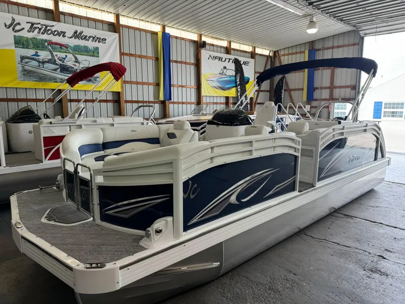 Slide: The Image of 2024 JC Neptoon 23 TT LG pontoon boat in showroom, blue and white design. - 4