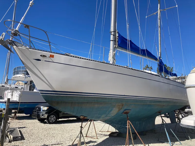 Slide: The Image of 1975 Northstar Hughs 80/20 sailboat with blue sails, docked on land. - 2