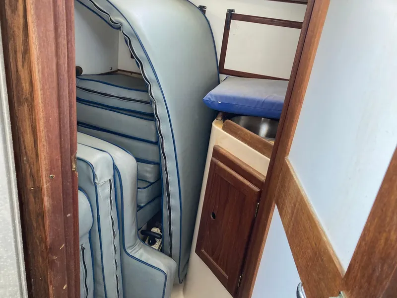 Slide: The Image of 1975 Northstar Hughs Northstar 80/20 cabin interior with stacked cushions and wooden cabinetry. - 20