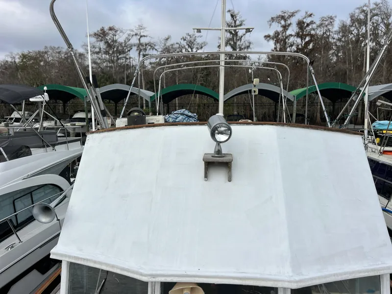 Slide: The Image of 1972 Grand Banks 42 Classic boat docked, front view with spotlight, surrounded by trees and other boats. - 13
