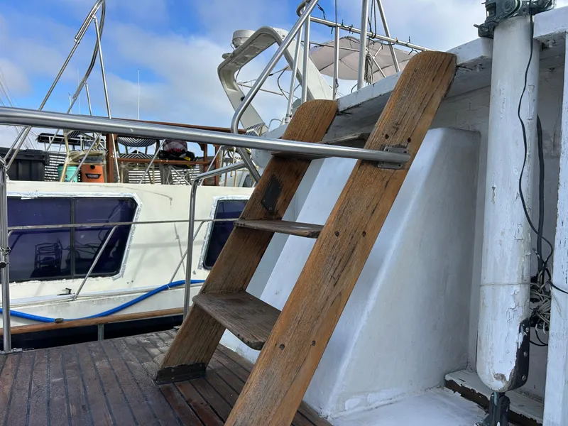 Slide: The Image of Wooden ladder on 1972 Grand Banks 42 Classic yacht deck, with railing and neighboring boat. - 22