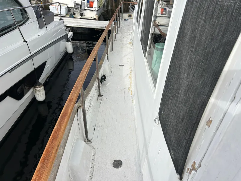 Slide: The Image of 1972 Grand Banks 42 Classic yacht deck with wooden railings, docked beside another boat. - 30
