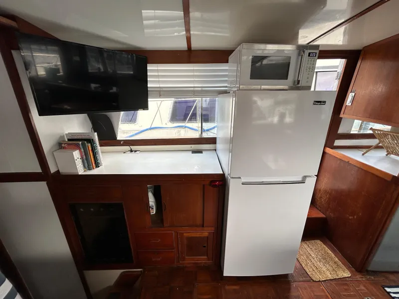 Slide: The Image of 1972 Grand Banks 42 Classic interior with fridge, microwave, TV, and wooden cabinetry. - 40