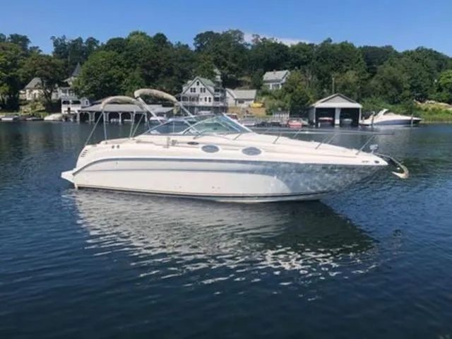 The Image of 2003 Sea Ray 260 Sundancer boat on a calm lake with houses in the background. - 1