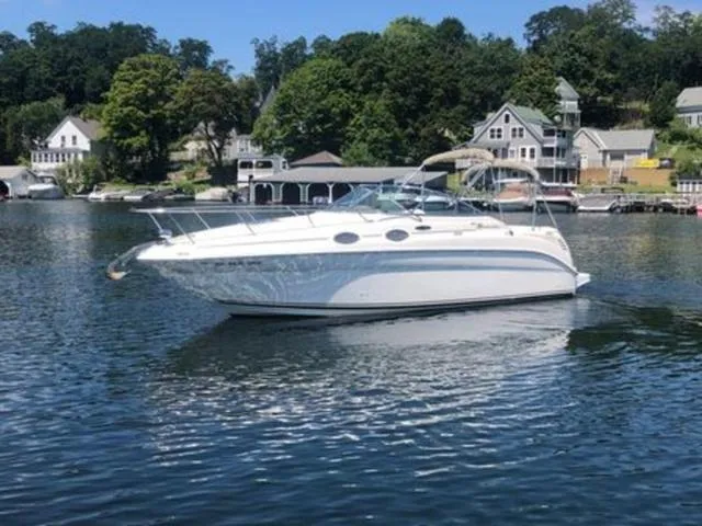 Slide: The Image of 2003 Sea Ray 260 Sundancer boat on a serene lake with houses in the background. - 3