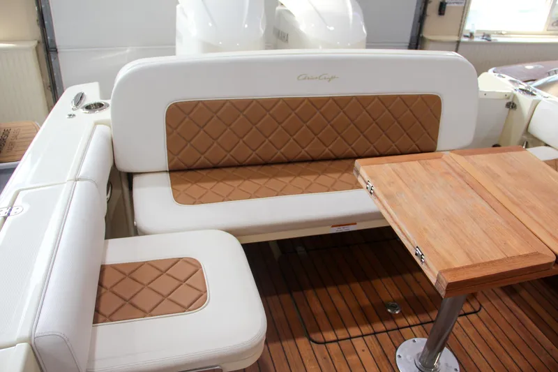 Slide: The Image of 2019 Chris-Craft Calypso 30 interior with tan diamond-stitched seating and wooden table. - 10