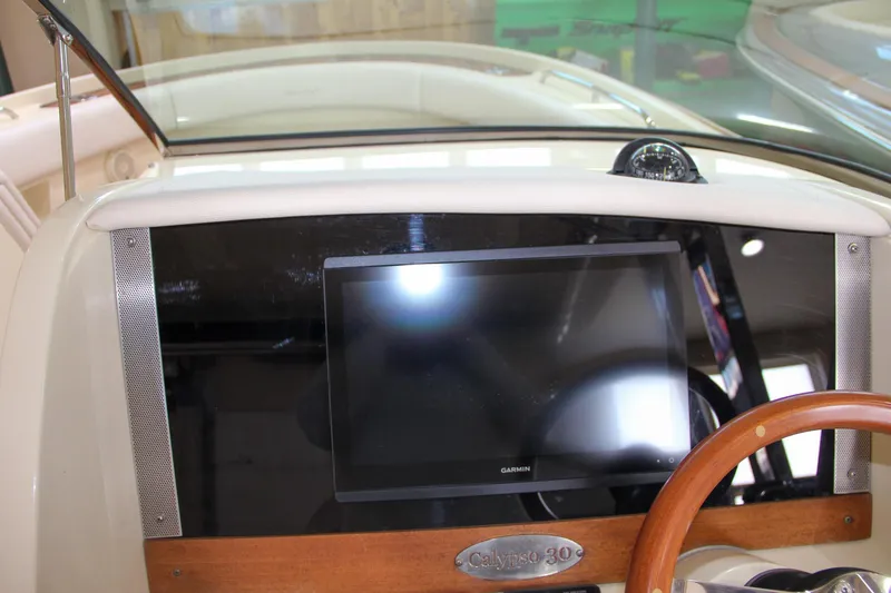 Slide: The Image of 2019 Chris-Craft Calypso 30 dashboard with Garmin display and wooden steering wheel. - 23