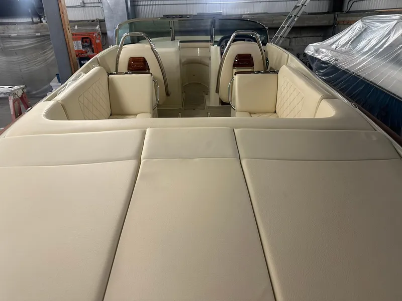 Slide: The Image of 2025 Chris-Craft Launch 27 boat interior with cream leather seating in a storage facility. - 7