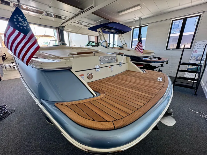 Slide: The Image of 2025 Chris-Craft Launch 27 boat with wooden deck and American flag in showroom. - 3