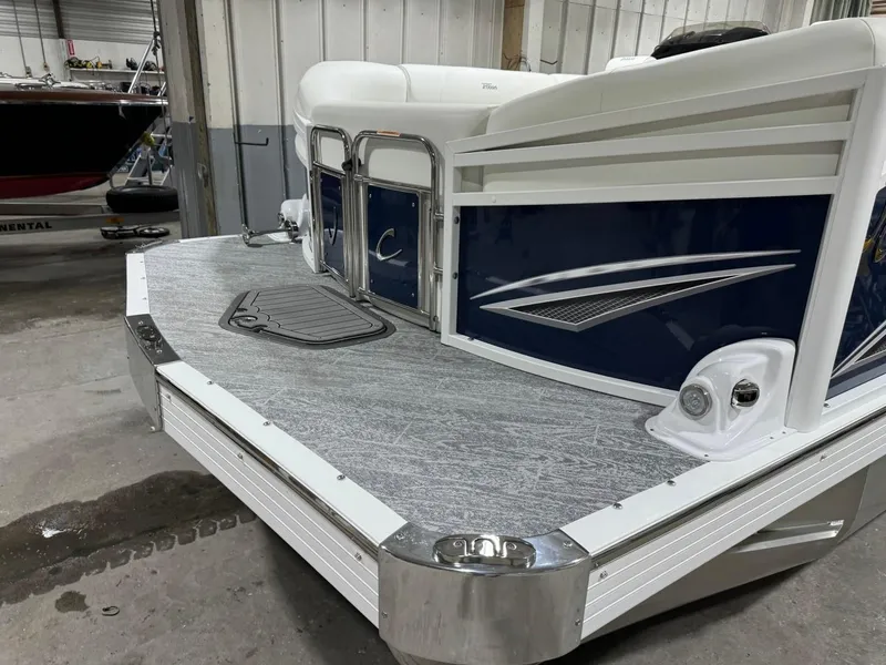 Slide: The Image of 2025 JC Swingback 25 TT pontoon boat in a showroom, featuring sleek design and modern detailing. - 2