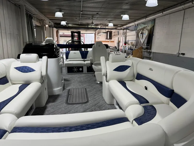 Slide: The Image of 2025 JC Swingback 25 TT pontoon boat interior with plush seating in a showroom. - 4