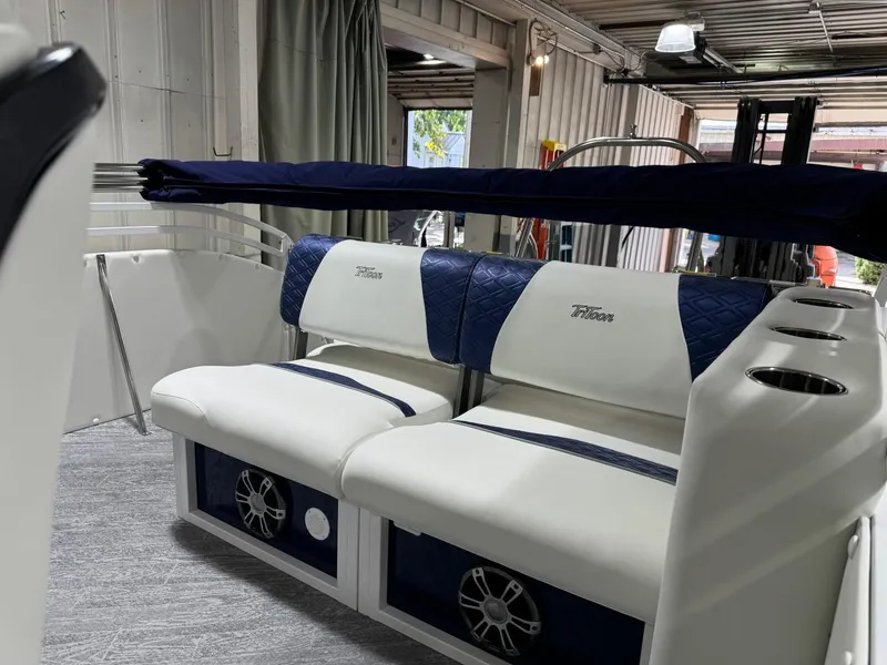 Slide: The Image of 2025 JC Swingback 25 TT boat interior with white and blue seating, cup holders, and speakers. - 6