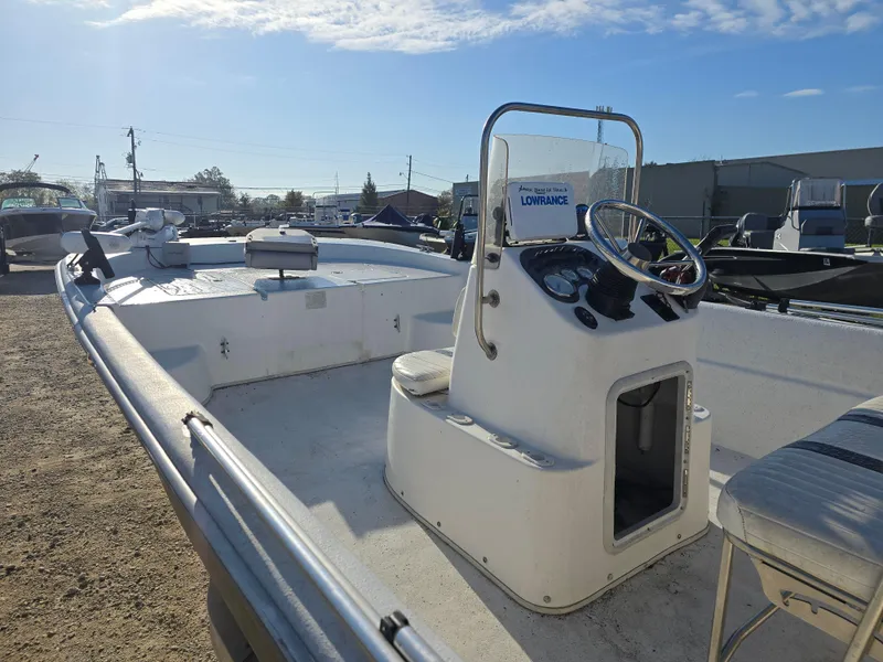 Slide: The Image of 2011 Carolina Skiff 218 DLV boat with steering console, parked outdoors under clear sky. - 6