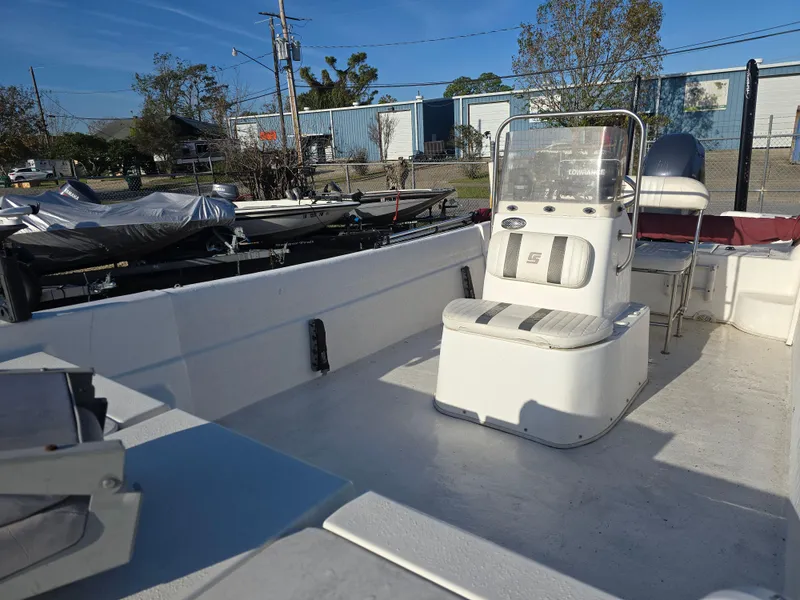 Slide: The Image of 2011 Carolina Skiff 218 DLV boat interior with seating and console, parked outdoors. - 9