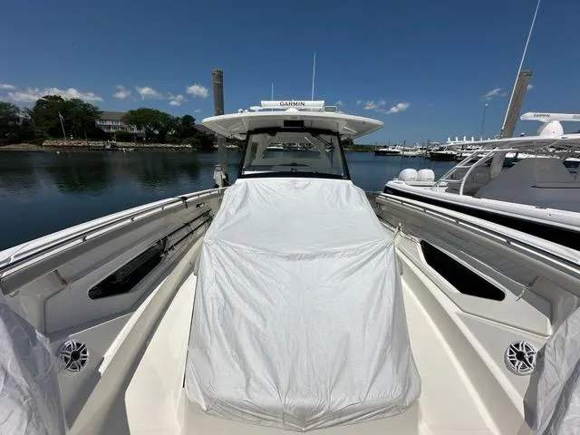 Slide: The Image of 2021 Pursuit S 428 Sport boat docked, covered, with clear skies and calm water. - 22