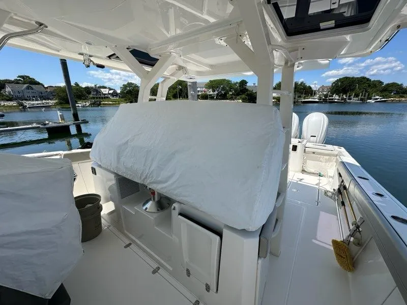 Slide: The Image of 2021 Pursuit S 428 Sport boat interior with covered seating, docked by a scenic waterfront. - 25