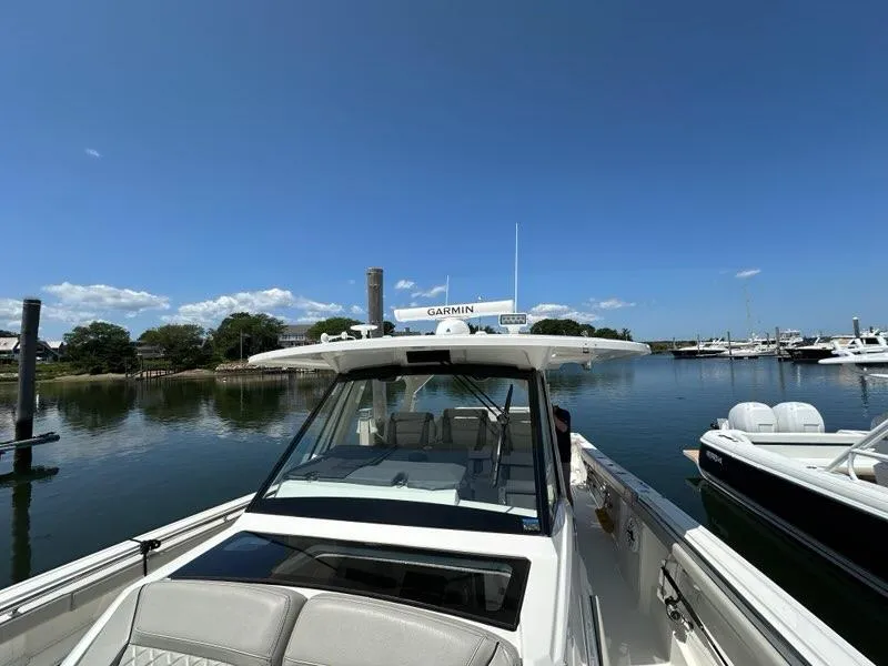 Slide: The Image of 2021 Pursuit S 428 Sport boat docked in a serene marina under clear blue skies. - 38