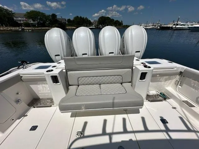 Slide: The Image of 2021 Pursuit S 428 Sport boat with quad engines and cushioned seating, docked by the water. - 9
