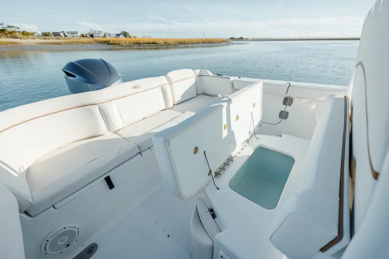 Slide: The Image of 2021 Sea Hunt Ultra 255 SE boat interior with seating and storage, on calm water. - 10