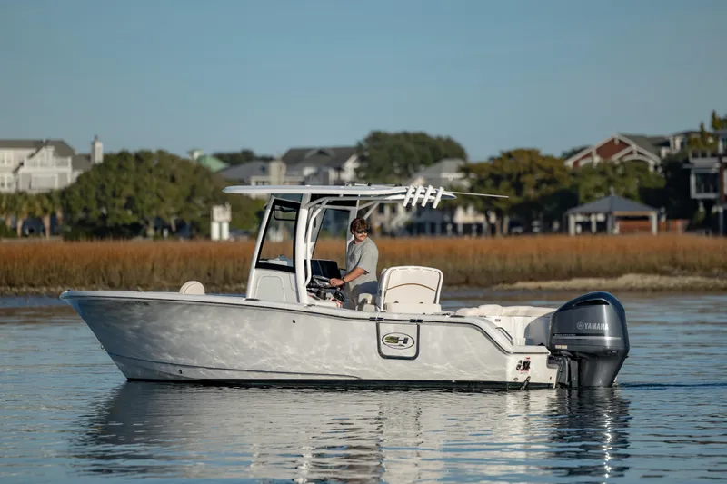 Slide: The Image of 2021 Sea Hunt Ultra 255 SE boat on calm water near shoreline. - 2