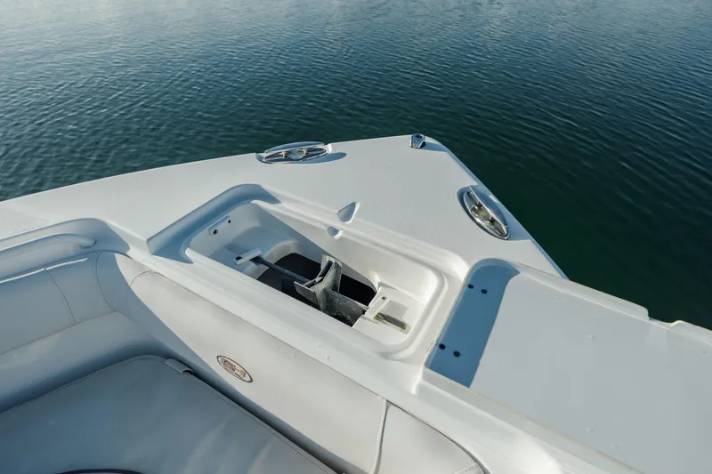 Slide: The Image of 2021 Sea Hunt Ultra 255 SE boat bow with anchor compartment on calm water. - 24