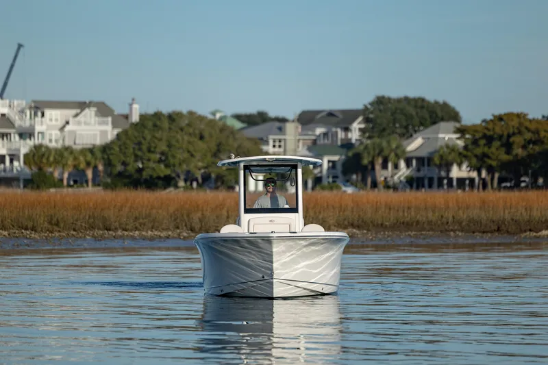 Slide: The Image of 2021 Sea Hunt Ultra 255 SE boat cruising on calm water near coastal homes. - 3