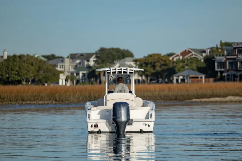 Slide: The Image of 2021 Sea Hunt Ultra 255 SE boat cruising on calm water near coastal homes. - 4