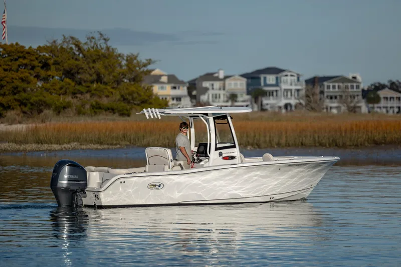 Slide: The Image of 2021 Sea Hunt Ultra 255 SE boat cruising on calm waters near coastal homes. - 5