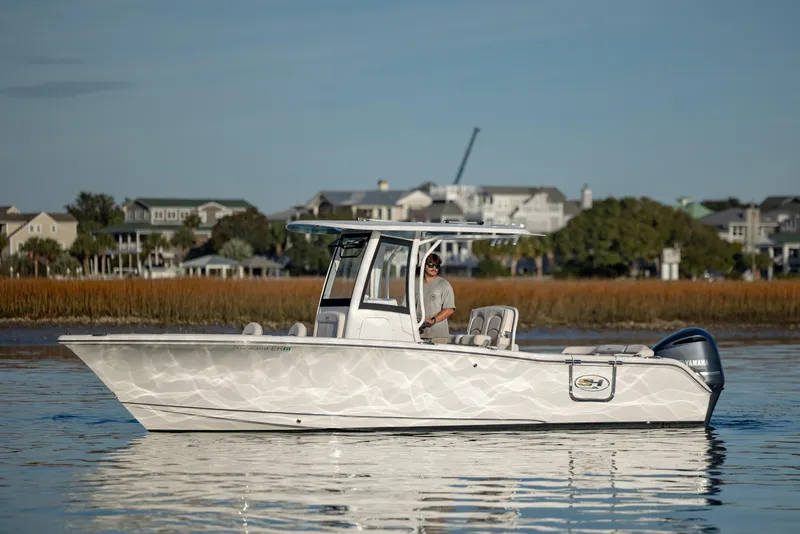 Slide: The Image of 2021 Sea Hunt Ultra 255 SE boat on calm water near coastal homes. - 6