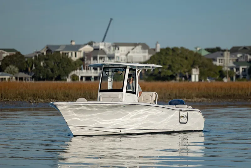 Slide: The Image of 2021 Sea Hunt Ultra 255 SE boat on calm water near coastal homes. - 7