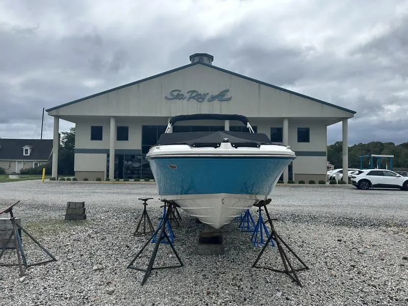 Slide: The Image of 2024 Sea Ray SPX 230 boat displayed outside dealership on gravel lot. - 2