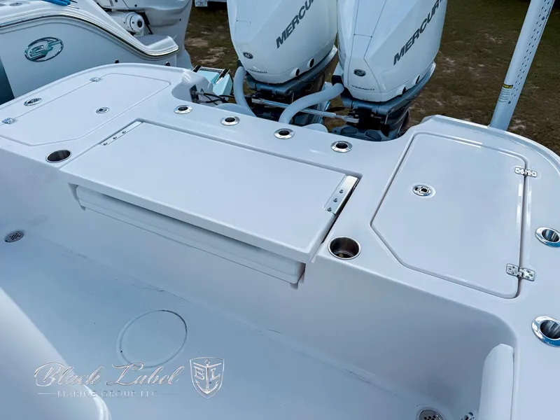 Slide: The Image of 2025 Caymas 281 HB boat deck with Mercury engines, featuring storage compartments and rod holders. - 23