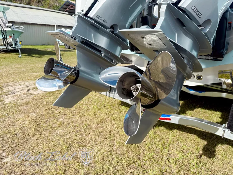 Slide: The Image of 2025 Caymas 281 HB boat propellers on grass, showcasing dual outboard motors. - 30