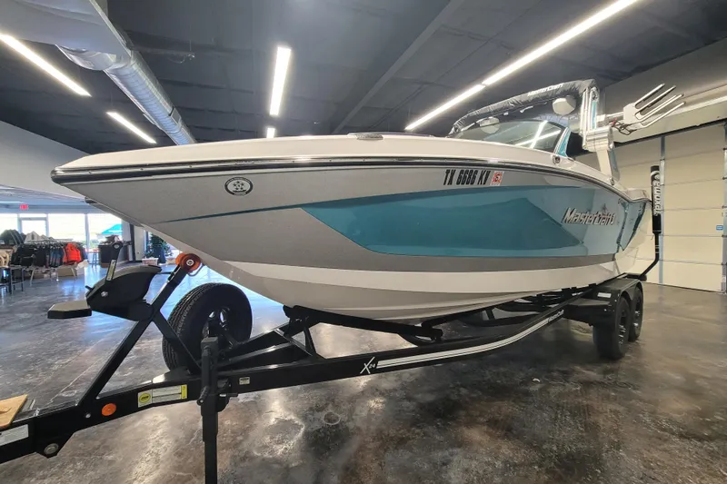 Slide: The Image of 2024 MasterCraft X24 boat on trailer in showroom, side view. - 3