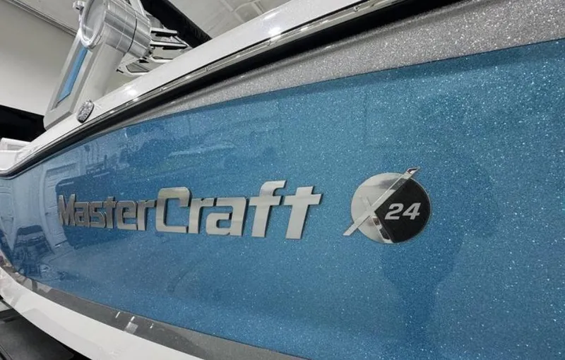 Slide: The Image of 2024 MasterCraft X24 boat interior with gray and white seating and logo flooring. - 9