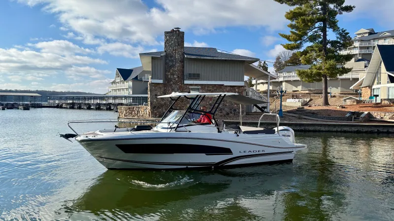 Slide: The Image of 2022 Jeanneau Leader 7.5 boat docked by lakeside houses under a blue sky. - 4