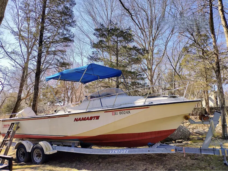 The Image of 1983 Boston Whaler 25 Revenge boat on trailer with blue canopy in wooded area. - 1