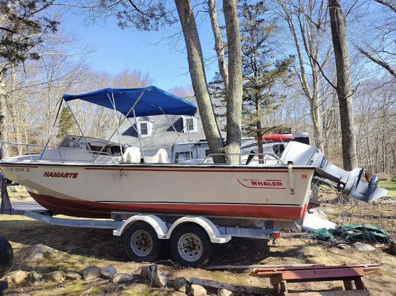 Slide: The Image of 1983 Boston Whaler 25 Revenge boat on trailer, parked outdoors with trees and house in background. - 10