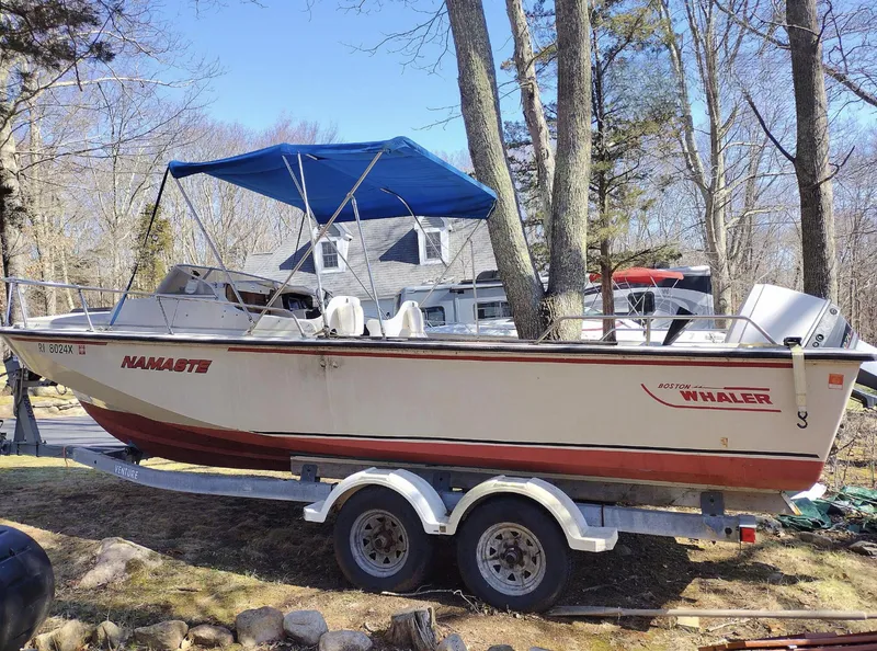 Slide: The Image of 1983 Boston Whaler 25 Revenge boat on trailer with blue canopy in wooded area. - 11