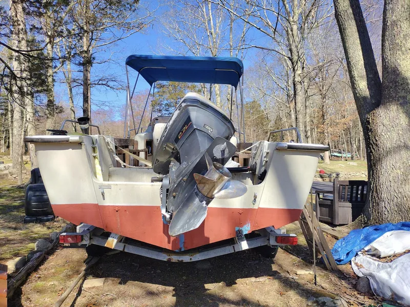 Slide: The Image of 1983 Boston Whaler 25 Revenge boat with outboard motor, parked on a trailer in a wooded area. - 19